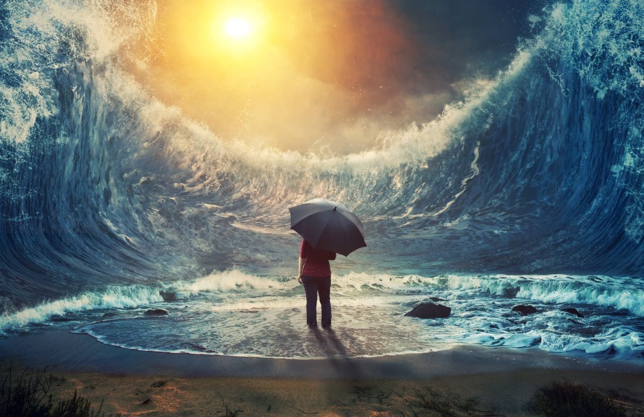 Person with umbrella facing giant ocean wave.